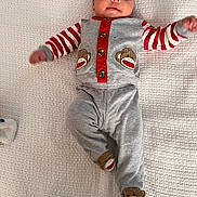 Christian joined the competition — help win amazing prizes! baby, infant, pajamas, monkey_design, grey_clothing, red_stripes, blanket, lying_down, cute, child, face, feet, hands, smiling, indoors, soft_texture, cozy, happy, playful, sleepwear