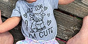 Kadence joined the competition — help win amazing prizes! baby, barefoot, cartoon, casual, child, clothing, cute, expression, funny_text, infant, legs, outdoor, person, planks, shirt, sitting, skin, summer, tattoo, wooden_deck