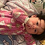 Jimena is registered to the contest to win money with this photo: baby, child, pajamas, pink_clothing, blanket, face, hand, hair, lying_down, indoor, cute, infant, sleepwear, patterned_clothing, floral_pattern, cartoon_blanket, comfort, portrait, sucking_thumb, young_child