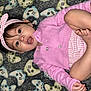 Jimena is registered to the contest to win money with this photo: baby, infant, pink_clothing, headband, carpet, game_controller_pattern, feet, hands, face, eyes, cute, child, indoor, portrait, laying_down, toddler, expression, skin, buttoned_cardigan, striped_onesie