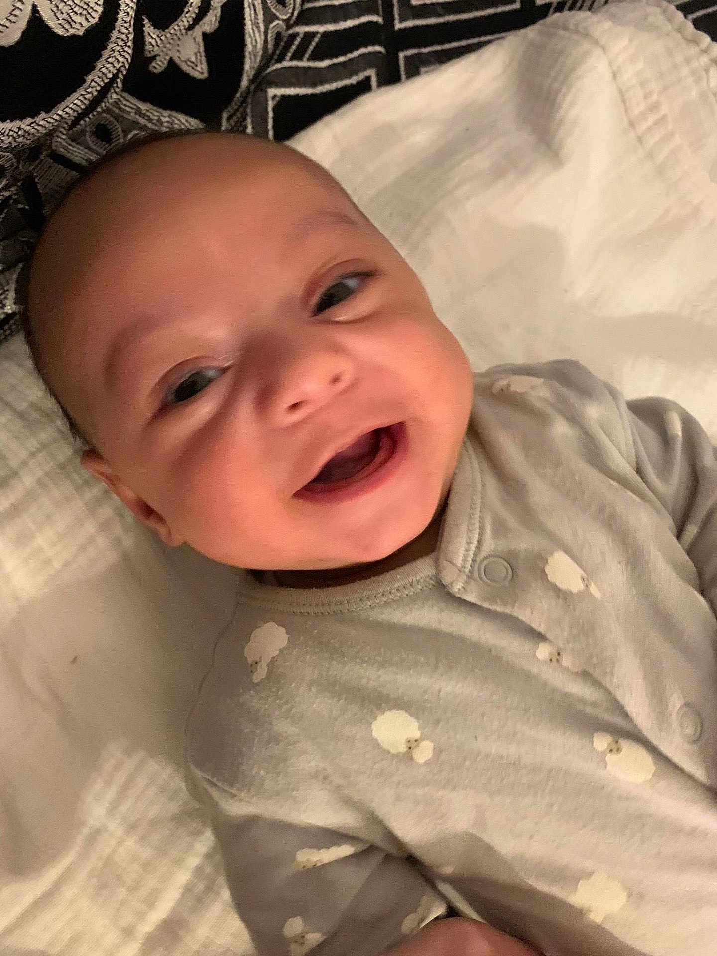 Raith a rejoint le concours — aidez-le/la à gagner de superbes lots ! baby, smiling, infant, onesie, cloud_pattern, blanket, pillow, happy, face, cute, lying_down, child, soft_texture, indoors, closeup, head, person, apparel, fabric, comfort