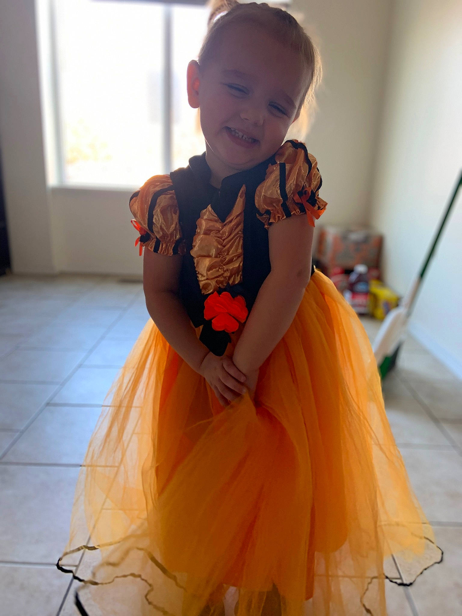 Octavia is registered to the contest to win money with this photo: baby_toddler_clothing, day_dress, dress, face, facial_expression, fashion_design, flooring, formal_wear, gown, happy, head, iris, joint, one_piece_garment, orange, person, sleeve, smile, standing, toddler