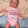 baby, infant, smiling, onesie, pink_clothing, blanket, bed, socks, cute, happy, child, lying_down, indoor, person, face, head, legs, skin, expression, cozy