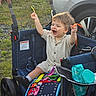 Kaison is registered to the contest to win money with this photo: toddler, stroller, toy, baby_wipes, outdoor, grass, car, child, happy, play, clothing, footwear, person, wheel, bag, seat, hand, face, smile, sunlight