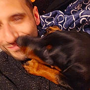Cora is registered to the contest to win money with this photo: man, dog, blur, close_up, affection, indoor, blanket, pattern, face, pet, canine, human, cuddle, warmth, cozy, love, interaction, snout, fur, head