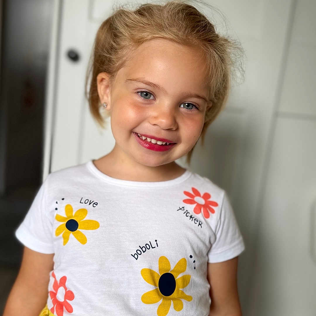 Zlata participe au concours pour gagner de l'argent avec cette photo : apparel, blonde_hair, child, clothing, cute, earrings, eyewear, face, fashion, flower_print, girl, happy, indoor, person, portrait, smiling, standing, tshirt, yellow_skirt, young
