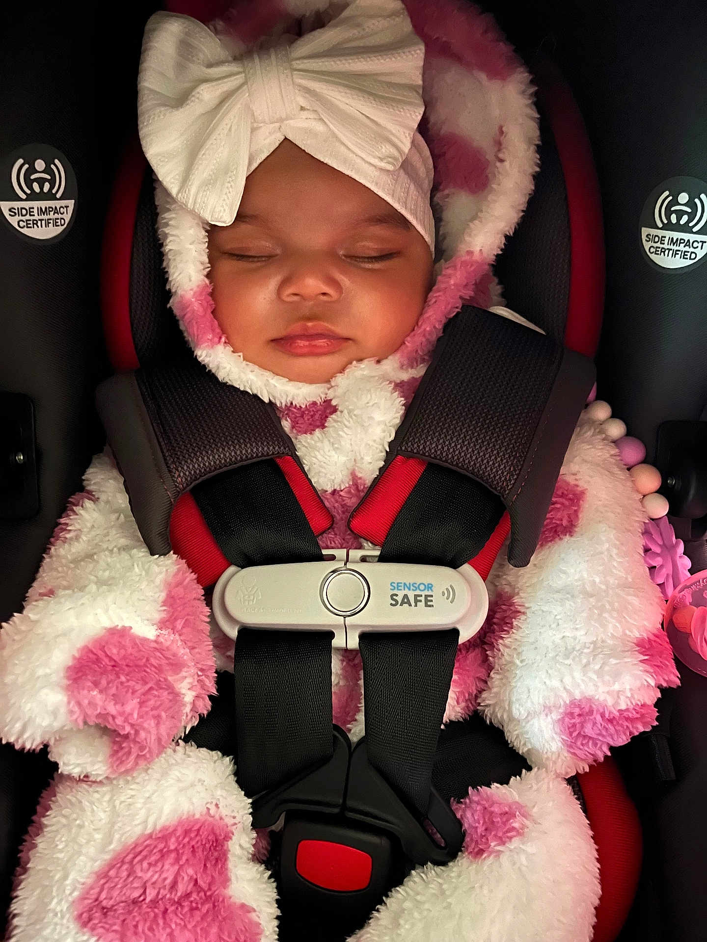 Divinity is registered to the contest to win money with this photo: baby, sleeping, car_seat, child, pink, white, bow, headband, onesie, fluffy, heart_pattern, harness, sensor_safe, cute, infant, warm_clothing, closed_eyes, toddler, seatbelt, safety
