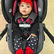 Divinity joined the competition — help win amazing prizes! baby, car_seat, red_headband, flower, infant, black_clothing, heart_pattern, leggings, red_booties, safety_harness, indoor, floor_tiles, cute, child, person, seated, adorable, wide_eyes, infant_fashion, expression