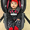 baby, car_seat, red_headband, flower, infant, black_clothing, heart_pattern, leggings, red_booties, safety_harness, indoor, floor_tiles, cute, child, person, seated, adorable, wide_eyes, infant_fashion, expression
