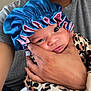 Divinity is registered to the contest to win money with this photo: baby, adult_hand, blue_bonnet, leopard_print, close_up, infant, face, person, holding, cute, newborn, clothing, pink, hand, skin, portrait, indoor, soft, tender, expression