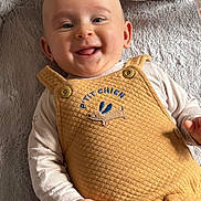 Isaac participe au concours pour gagner de l'argent avec cette photo : baby, infant, smiling, portrait, overalls, onesie, soft_toy, blanket, lying_down, happy, face, eyes, tongue, cheeks, hand, embroidery, buttons, fabric_texture, indoor, cozy