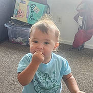 Courtlan is registered to the contest to win money with this photo: toddler, child, indoor, carpet, blue_shirt, dinosaur_print, baby, hand_in_mouth, curly_hair, toy_storage, plastic_bin, training_pants_box, casual_clothing, young_child, face, person, expression, cute, home, floor
