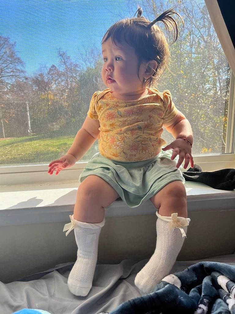 Annie is registered to the contest to win money with this photo: arm, child, cool, fun, grass, hand, happy, human_leg, knee, lap, leisure, outdoor_play_equipment, person, recreation, shorts, sky, sock, thigh, tints_and_shades, toddler