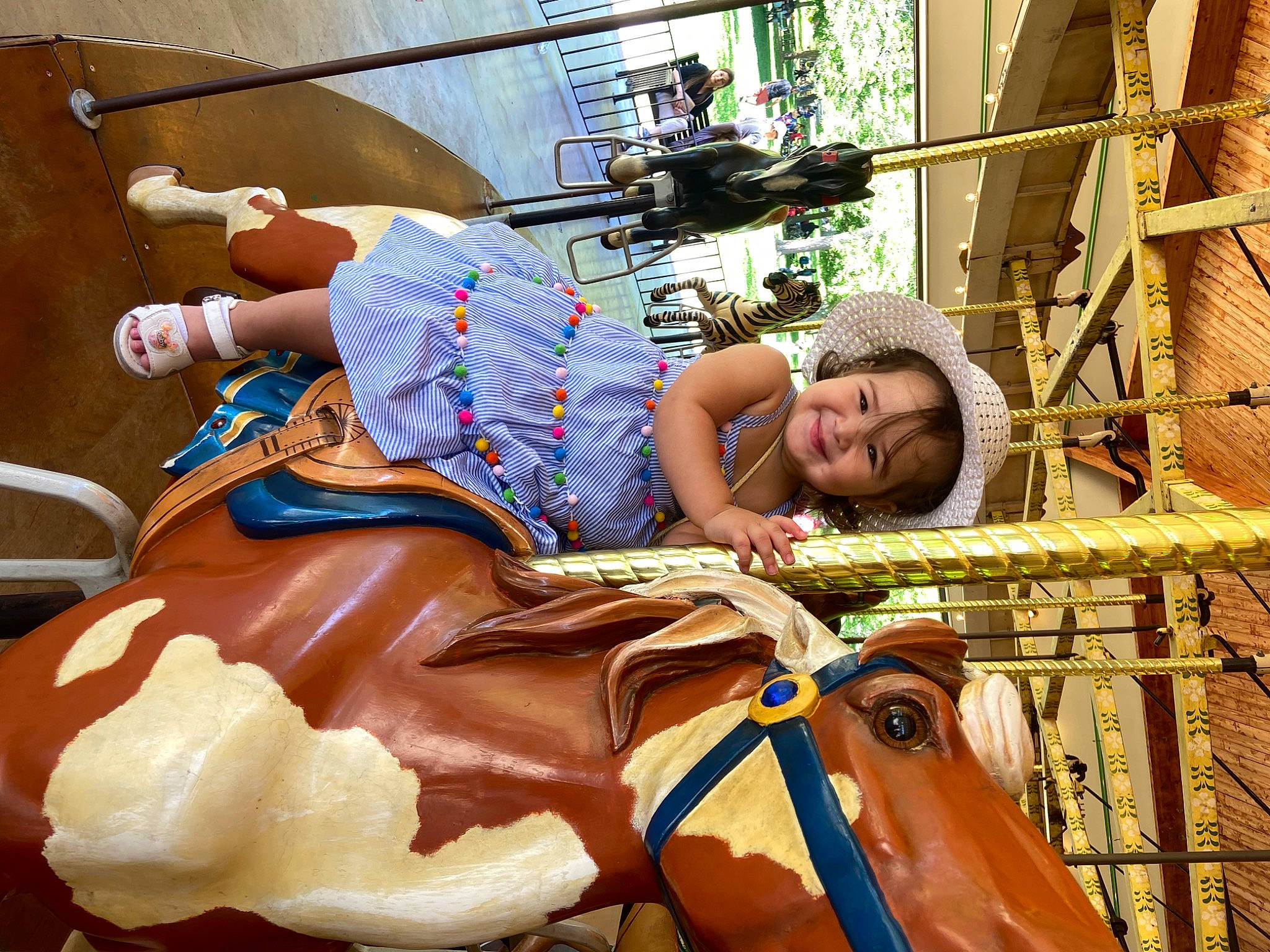 Annie is registered to the contest to win money with this photo: amusement_ride, bovine, bridle, bull, carousel, event, fun, hat, horse_supplies, horse_tack, joy, leisure, livestock, pack_animal, person, recreation, rein, saddle, temple, toddler