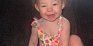 Alayna is registered to the contest to win money with this photo: toddler, child, smiling, sitting, couch, orange_bow, floral_outfit, happy, indoors, baby, cute, person, young_child, skin, face, hand, foot, hair, furniture, portrait
