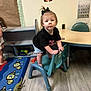 Alayna joined the competition — help win amazing prizes! toddler, child, chair, toy, classroom, floor, carpet, poster, table, black_tshirt, shorts, bow, person, indoor, wood_floor, educational, animal_toy, furniture, young_child, cute
