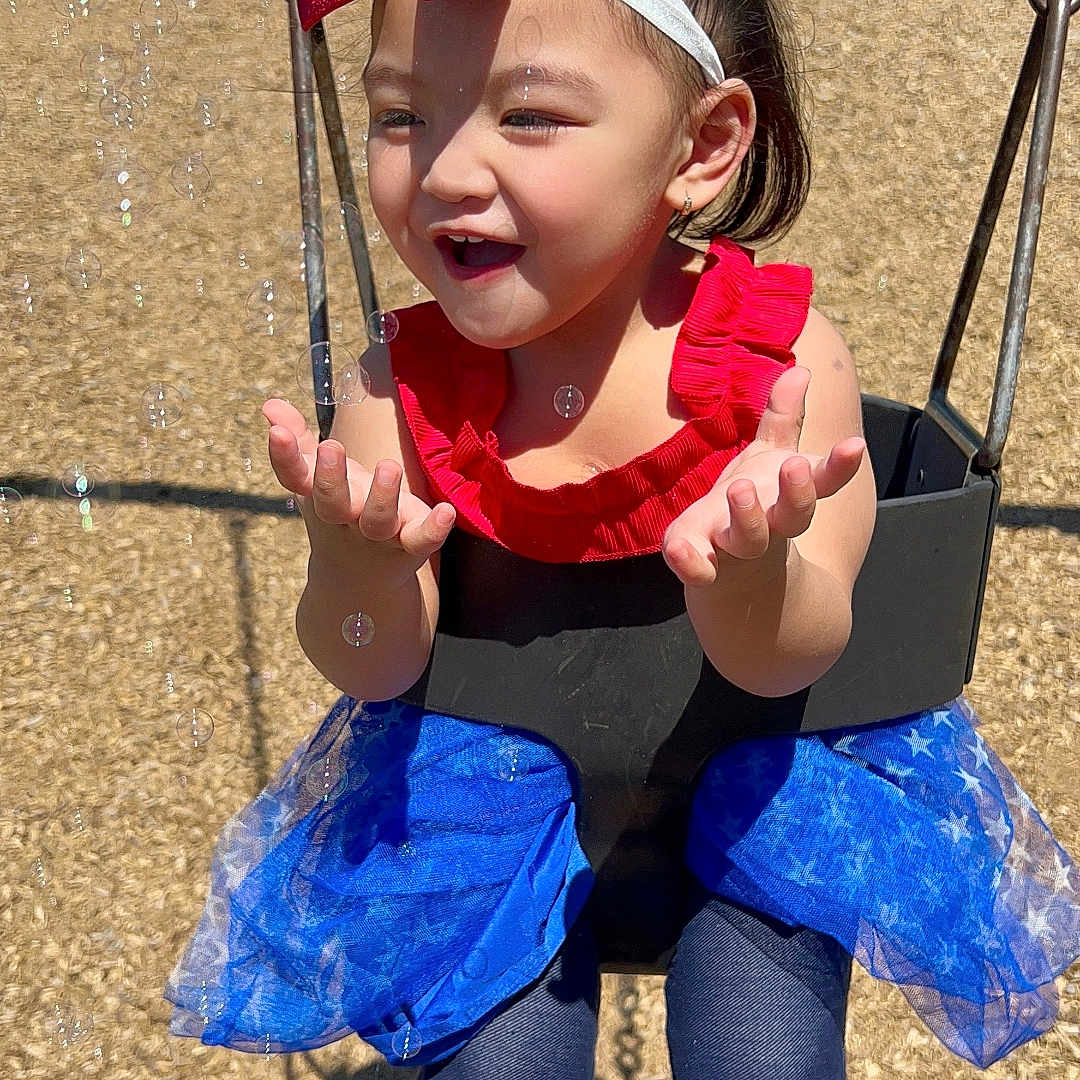 Ellyza Kaylee is registered to the contest to win money with this photo: blue_tutu, bubbles, child, clothing, face, fun, happy, leggings, outdoor, park, person, pigtails, play, playground, red_bow, smiling, sunny, swing, toddler, toy