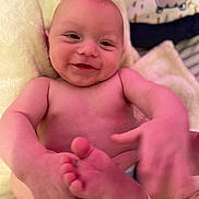 Riley is registered to the contest to win money with this photo: baby, infant, child, smiling, happy, portrait, face, eyes, nose, mouth, bare_skin, lying_down, blanket, pillow, bed, cozy, indoor, close_up, toes, photography