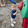 Riley joined the competition — help win amazing prizes! child, toddler, playground, play_equipment, slide, outdoor, park, portrait, standing, reaching, serious_expression, blue_shirt, gray_shorts, white_shoes, wood_chips, colorful, green_structure, red_structure, daylight, playtime