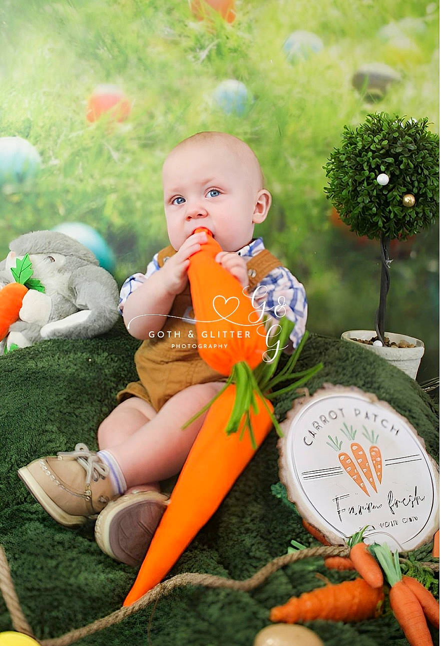 Jaxton is registered to the contest to win money with this photo: baby, child, doll, garden, grass, green, happy, holiday, human_leg, lawn_ornament, leaf, leisure, orange, ornament, people_in_nature, person, plant, sitting, spring, toddler
