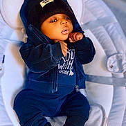 Néis a rejoint le concours — aidez-le/la à gagner de superbes lots ! baby, child, infant, hoodie, beanie, clothing, sitting, cushion, soft, indoor, cute, portrait, face, hands, footwear, dark_blue, casual, relaxed, young, cozy