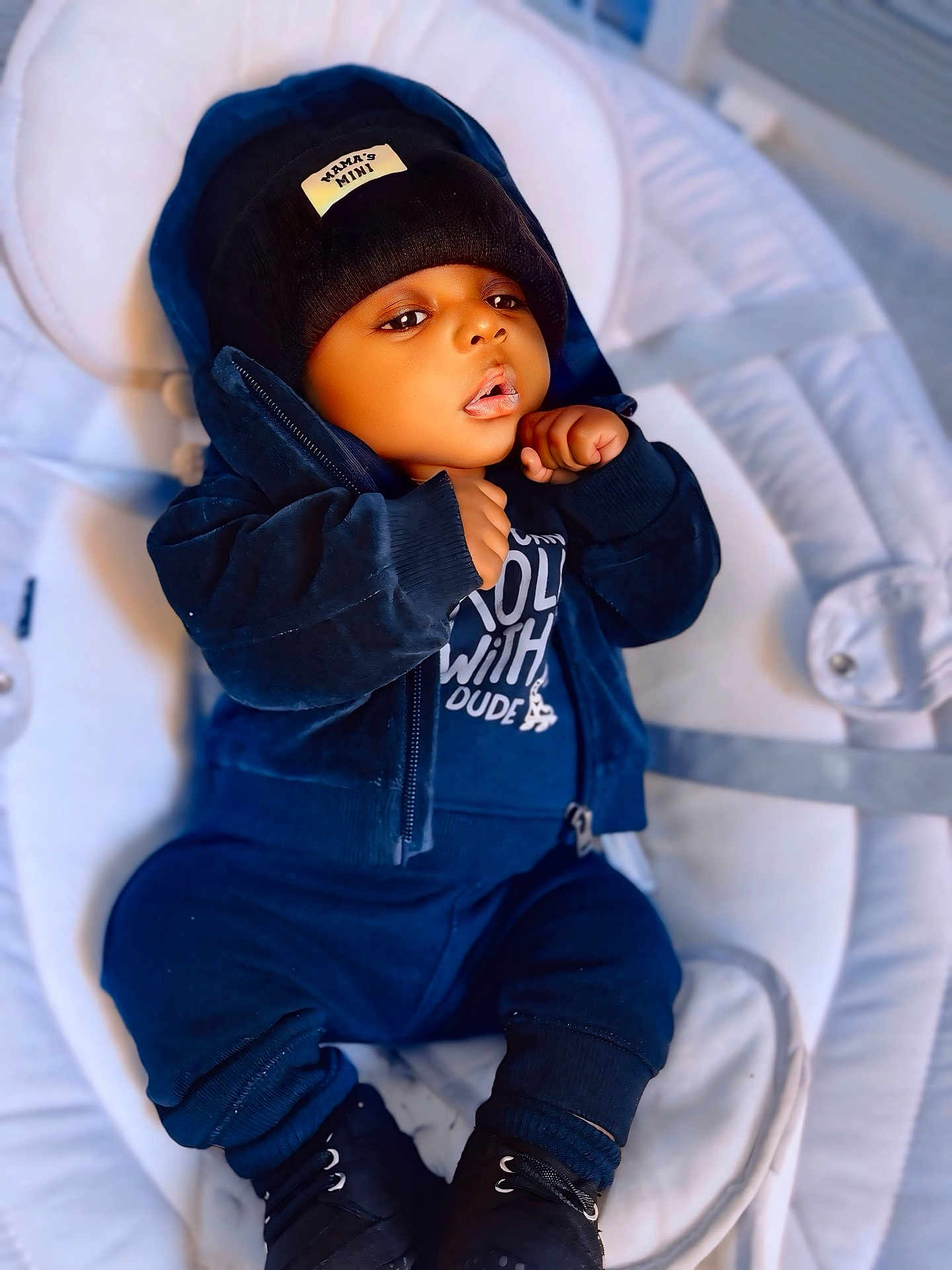Néis a rejoint le concours — aidez-le/la à gagner de superbes lots ! baby, child, infant, hoodie, beanie, clothing, sitting, cushion, soft, indoor, cute, portrait, face, hands, footwear, dark_blue, casual, relaxed, young, cozy