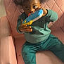 Jireh joined the competition — help win amazing prizes! afro_hair, barefoot, casual_clothing, child, curious, furniture, green_pants, green_sweater, home, indoor, looking_away, pacifier, pink_chair, playful, portrait, relaxed, sitting, toddler, toy, young_child