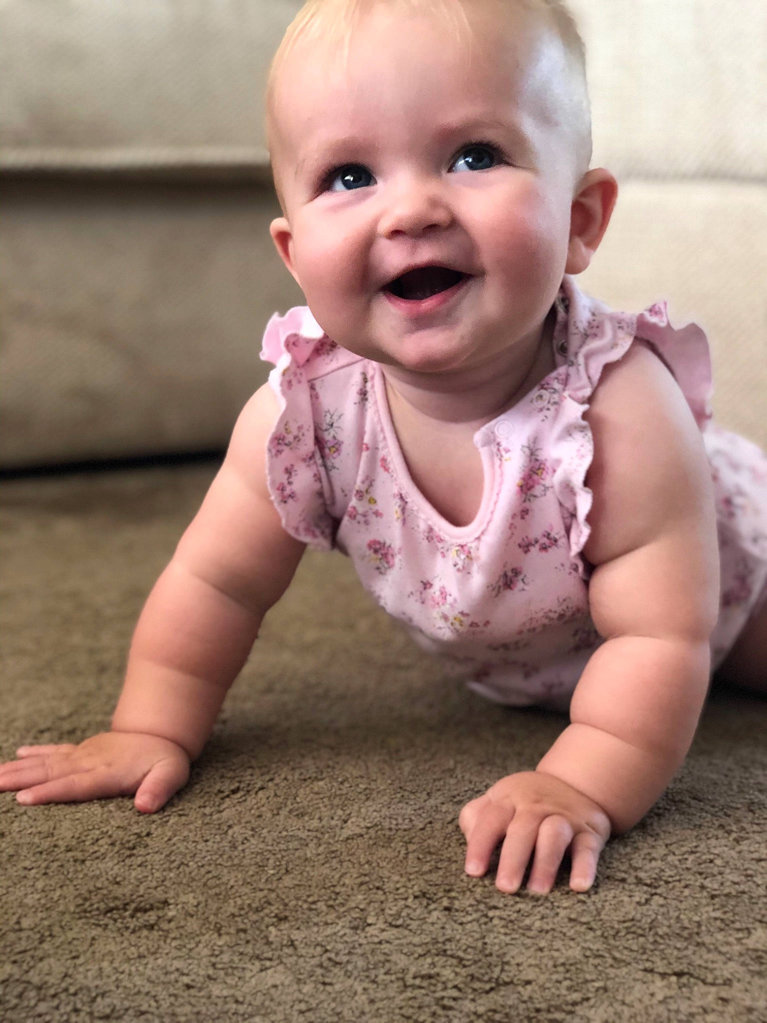 Esther is registered to the contest to win money with this photo: baby, baby_toddler_clothing, cheek, child, crawling, face, facial_expression, flooring, head, laugh, mouth, person, play, sitting, skin, smile, toddler, tummy_time