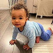 Isaac participe au concours pour gagner de l'argent avec cette photo : child, baby, toddler, crawling, curly_hair, blue_pajamas, hardwood_floor, area_rug, couch, living_room, smiling, hands, knees, bare_feet, radiator, furniture, indoor, portrait, playful, cute