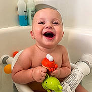 Ozzy is registered to the contest to win money with this photo: baby, bath, bathtub, child, clean, cute, fun, green, happy, holding, infant, orange, person, plastic, play, sitting, skin, smile, toy, water