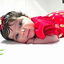 Vanessa is registered to the contest to win money with this photo: baby, infant, child, red_dress, flower_headband, cute, portrait, face, eyes, lying_down, soft_surface, indoors, white_background, daisy_pattern, toddler, smiling, skin, hair, closeup, adorable
