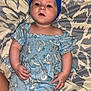 Josetta is registered to the contest to win money with this photo: baby, child, blue_headband, blue_dress, elephant_pattern, diaper, bedspread, patterned_bedspread, infant, lying_down, curious_expression, small_hands, soft_skin, indoors, casual, cute, portrait, person, clothing, headwear