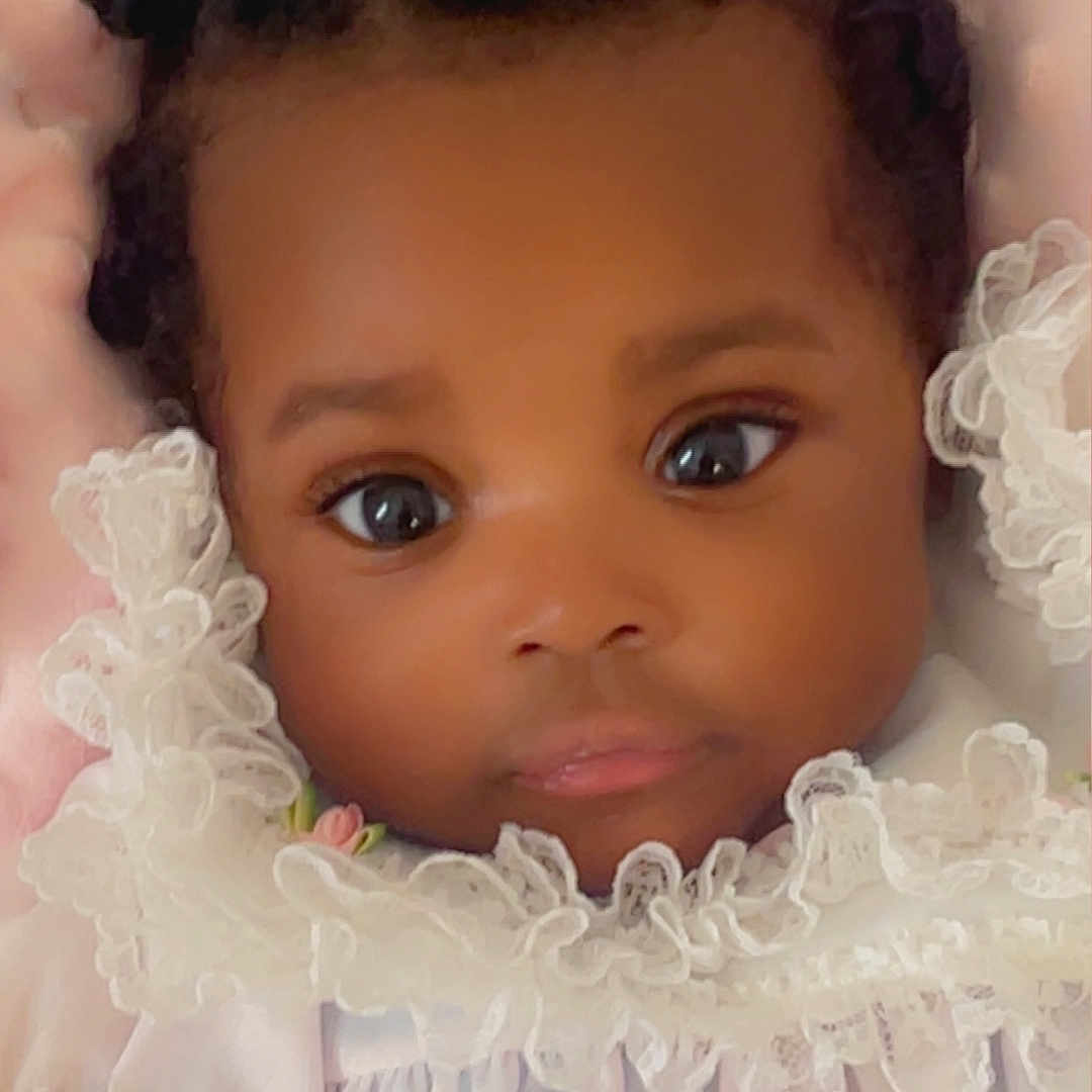 Jaminah joined the competition — help win amazing prizes! adorable, baby, big_eyes, black_hair, child, close_up, clothing, curly_hair, cute, face, frills, hands, indoor, infant, lace, newborn, pink_background, portrait, soft, white_dress