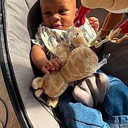 Omeer is registered to the contest to win money with this photo: baby, infant, child, car_seat, plush_toy, giraffe, toy, bib, smiling, sitting, portrait, face, sunlight, indoor, clothing, denim, safety_harness, baby_gear, cozy, photography