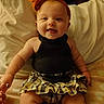 Everleigh joined the competition — help win amazing prizes! baby, child, smiling, headband, orange, black_top, plaid_skirt, sitting, bed, pillow, blanket, indoors, cute, happy, infant, person, portrait, young_child, clothing, skin