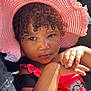 child, toddler, hat, pink_hat, curly_hair, car_seat, sunlight, orange_sippy_cup, red_clothing, cartoon_character, hand, face, eyes, portrait, indoors, car_interior, seatbelt, cute, baby, summer