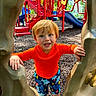 active, casual_clothing, child, climbing_structure, daylight, fun, happy, kid, nature, orange_shirt, outdoor, park, play, play_equipment, playground, recreation, red_hair, slide, smiling, trees