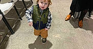 Kingslyn Kole is registered to the contest to win money with this photo: adults, brown_pants, casual, child, clothing, concrete_floor, curious, event, folding_chairs, indoor, people, person, plaid_shirt, red_hair, shadow, shoes, standing, toddler, vest, walking