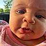 baby, close_up, face, blue_eyes, pink_clothing, blanket, outdoor, daylight, infant, curious_expression, portrait, child, young_baby, cute, skin, head, person, sunlight, warm, cozy