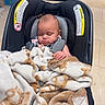 baby, car_seat, blanket, sleeping, child, indoor, store, shopping, teddy_bear_pattern, clothing, person, infant, comfort, resting, seatbelt, floor, box, shelf, shopping_cart, tiled_floor