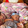 baby, sleeping, blanket, unicorn, plush_toy, teddy_bear, ribbon, couch, floral_pattern, headband, blue_dress, white_leggings, cozy, child, indoor, furniture, soft_texture, peaceful, resting, cute