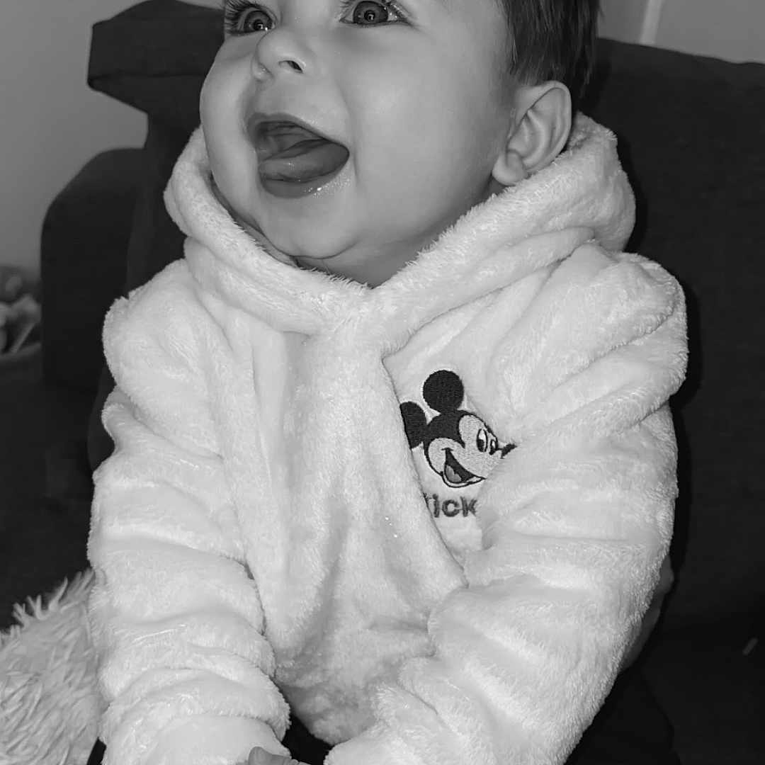 Kayron participe au concours pour gagner de l'argent avec cette photo : baby, black_and_white, child, closeup, couch, cozy, cute, eyelashes, fuzzy, hands, high_contrast, hoodie, indoor, infant, laughing, mickey_mouse, portrait, sitting, smile, socks