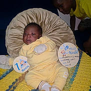 Nicodemus joined the competition — help win amazing prizes! baby, child, yellow_clothing, pillow, blanket, milestone_sign, indoor, couch, sibling, curious, knitted_blanket, portrait, cute, infant, smiling, face, person, home, cozy, family