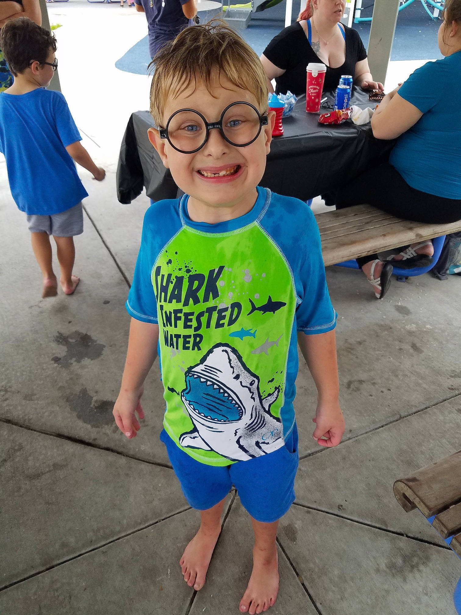 Kodi is registered to the contest to win money with this photo: bench, blue, child, clothing, electric_blue, event, eyewear, fun, glasses, happy, headwear, joy, leisure, natural_environment, person, recreation, shoe, shorts, sleeve, smile