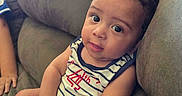 Dj is registered to the contest to win money with this photo: baby, casual, child, couch, curly_hair, cute, expression, face, furniture, hand, indoor, infant, looking_at_camera, portrait, relaxed, seated, skin, striped_clothing, tank_top, young