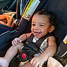 Dj is registered to the contest to win money with this photo: arm, baby, car_seat, child, clothing, curly_hair, cute, face, hand, happy, infant, inside, person, safety, seat, seatbelt, smile, transportation, vehicle, young