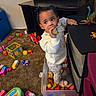 Kailani is registered to the contest to win money with this photo: toddler, child, toy, dinosaur, plastic_bin, carpet, playroom, drawer, furniture, indoor, clothing, curly_hair, footwear, colorful, scattered_toys, person, young_child, play, exploration, standing