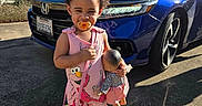 Kailani joined the competition — help win amazing prizes! toddler, child, pacifier, pink_outfit, elmo, doll, small_purse, sneakers, blue_car, sunlight, outdoor, concrete, trees, house, shoes, toy, daytime, person, cute, smiling