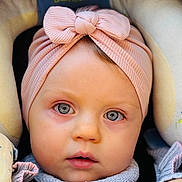 Lyv a rejoint le concours — aidez-le/la à gagner de superbes lots ! baby, headband, pink, blue_eyes, face, portrait, close_up, infant, child, car_seat, soft_lighting, curious_expression, clothing, knitwear, seat_belt, baby_accessory, cute, young_child, warm_tones, indoor