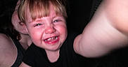Dryker is registered to the contest to win money with this photo: adult, blond_hair, casual_clothing, child, close_up, dark_background, expression, face, happy, human, indoor, joy, person, portrait, reaching_hand, selfie, short_hair, skin, smiling, toddler